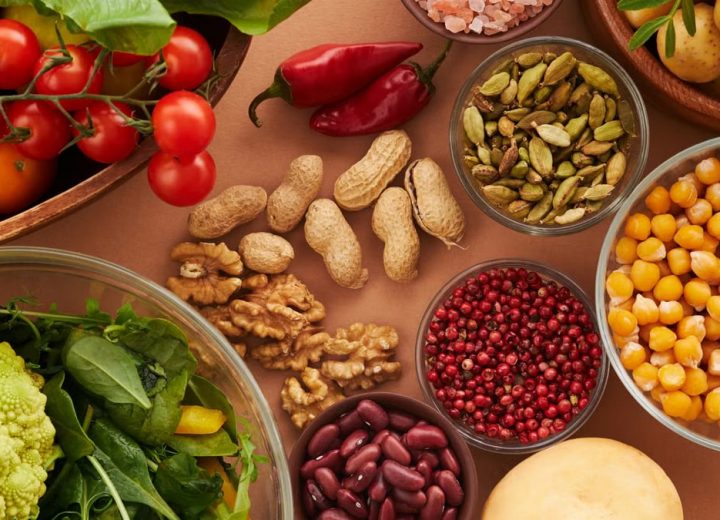 Explore a colorful assortment of healthy ingredients, featuring vegetables, nuts, seeds, and spices in a top view layout.